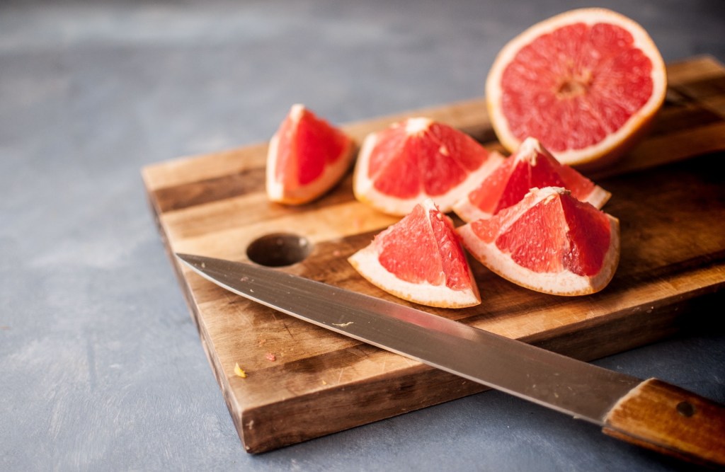 A grapefruit sliced open on a wooden chopping board
